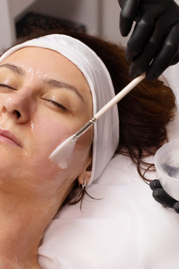 closeup-beauty-therapist-applying-face-mask-woman-with-perfect-fresh-skin