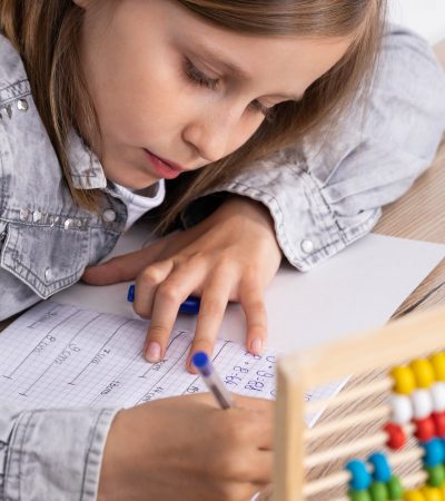 The schoolgirl solves the task. The girl writes in a notebook with a pen. Primary school.