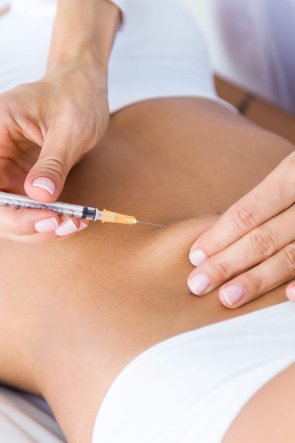 Portrait of surgeon making injection into female body. Liposuction concept.
